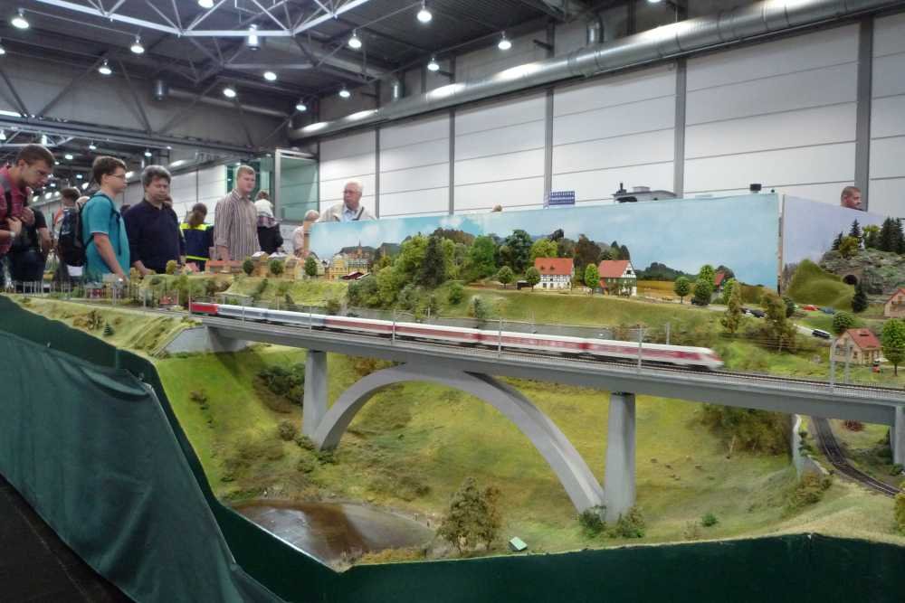 Modellbahnanlage mit Talbrücke und Besuchern auf der Messe Modell Hobby Spiel in Leipzig