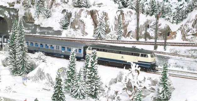 Personenzug fährt durch eine verschneite Winterlandschaft, H0-Anlage